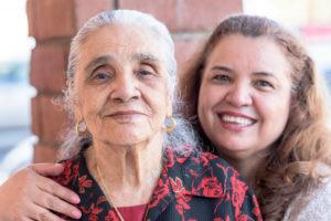 Smiling hispanic mother and daughter posing together