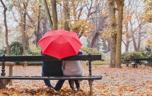 people under red umbrella in the park in fall