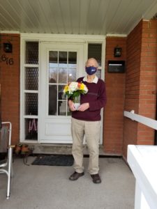 Dave standing outside holding a bouquet of flowers.